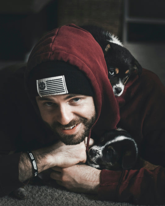 smiling man lying on floor together with black and white puppies