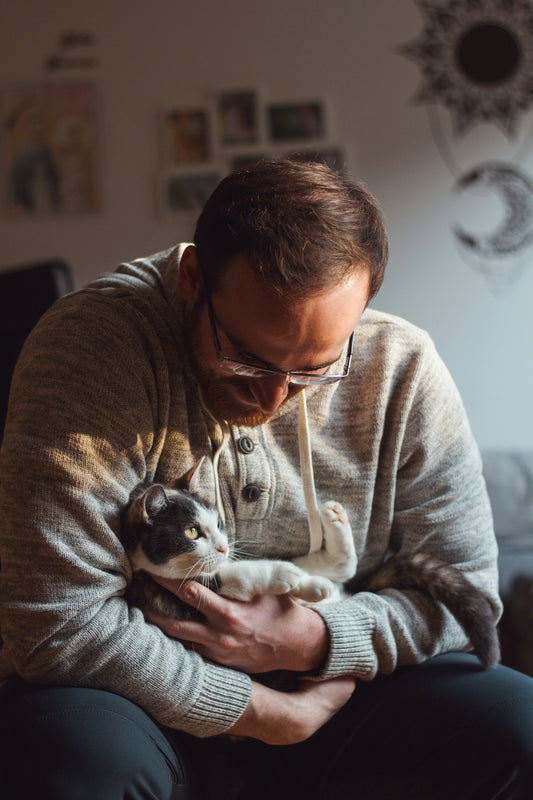 woman in gray sweater holding black and brown puppy