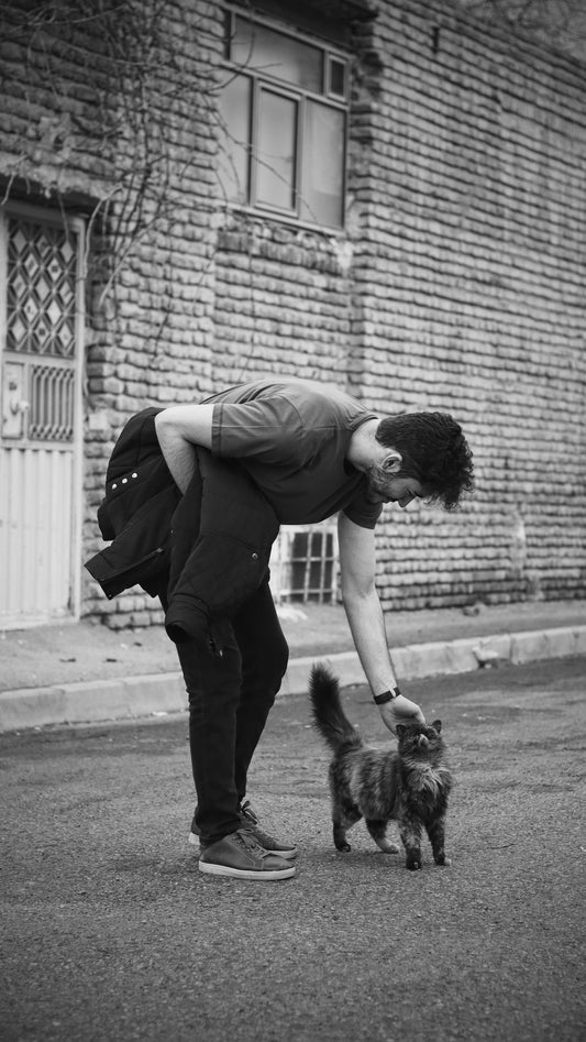 man in black jacket hugging black and white dog