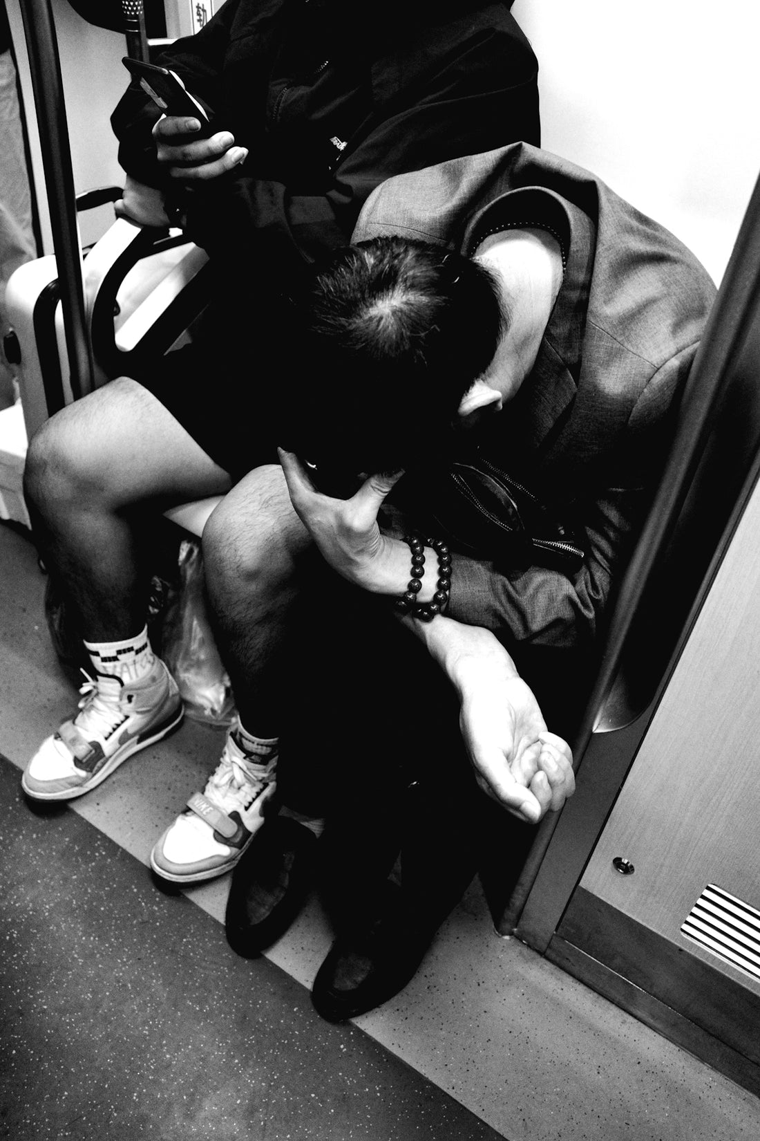 a man sitting on a subway looking at his cell phone